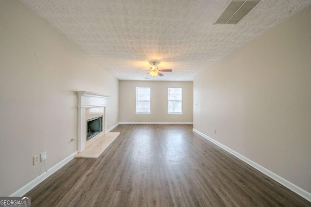 unfurnished living room featuring dark hardwood / wood-style flooring, ceiling fan, and a textured ceiling