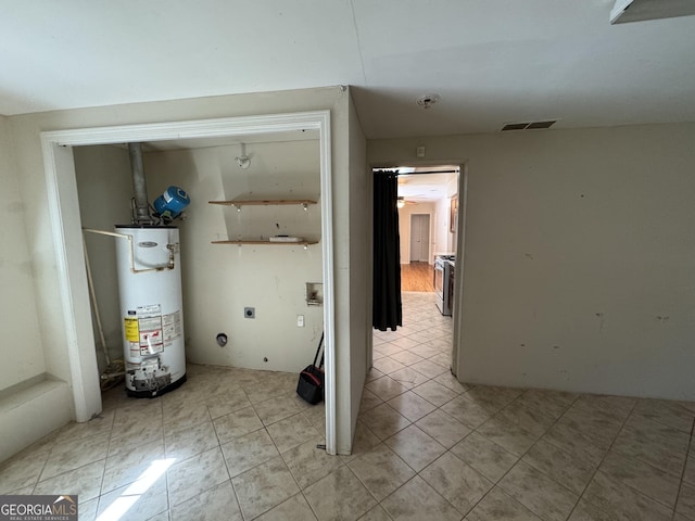 laundry room featuring electric dryer hookup, light tile patterned floors, and water heater