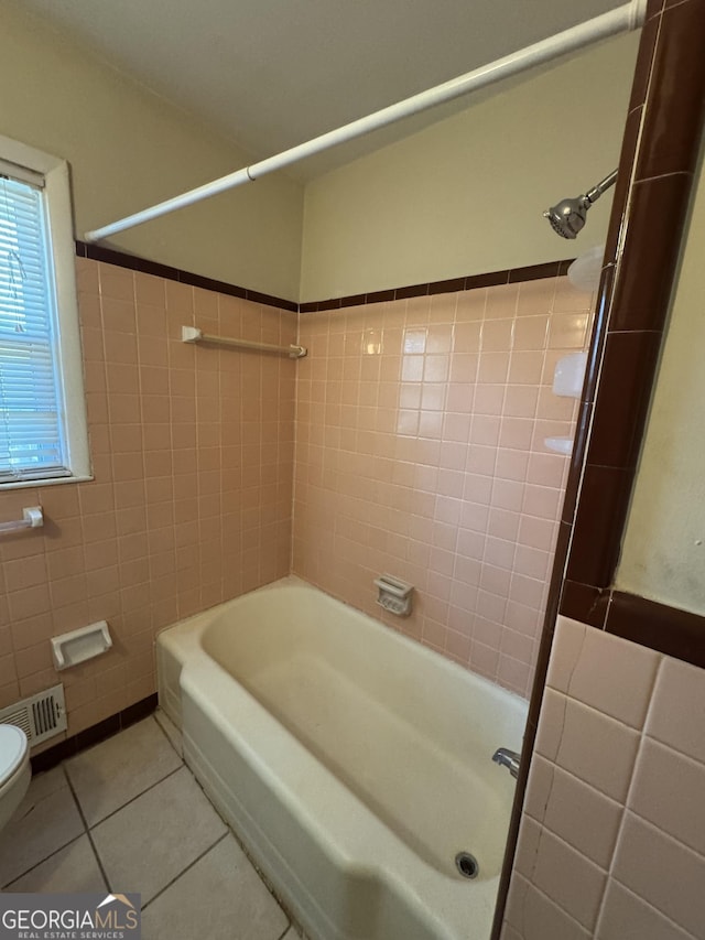 bathroom featuring tile patterned flooring, toilet, and tile walls