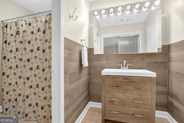 bathroom featuring visible vents, curtained shower, vanity, and tile walls