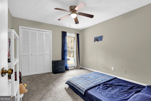 carpeted bedroom featuring baseboards, a textured ceiling, a ceiling fan, and a closet