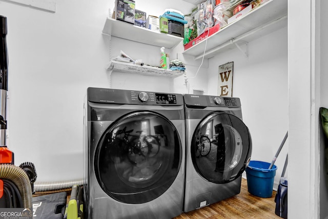 clothes washing area with laundry area, washer and clothes dryer, and wood finished floors