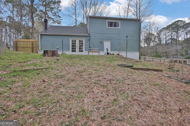 rear view of property with french doors, fence, and a lawn