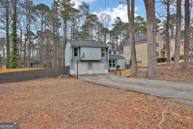 view of front facade featuring a garage, a residential view, fence, and driveway