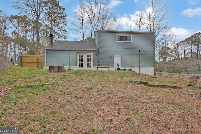 rear view of property featuring french doors, fence, and a lawn