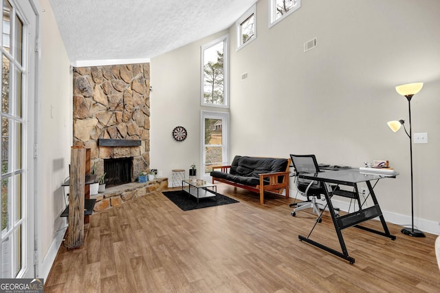 office featuring visible vents, a fireplace, a textured ceiling, and wood finished floors