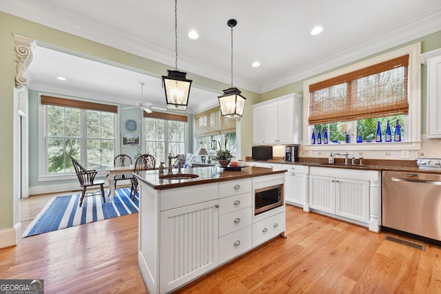 kitchen with stainless steel appliances, an island with sink, sink, and white cabinets