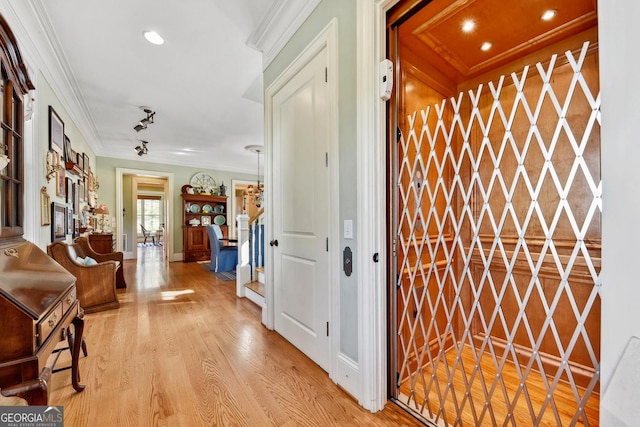 foyer with ornamental molding, elevator, and light wood-type flooring