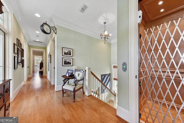 entryway with crown molding, a notable chandelier, and light hardwood / wood-style flooring