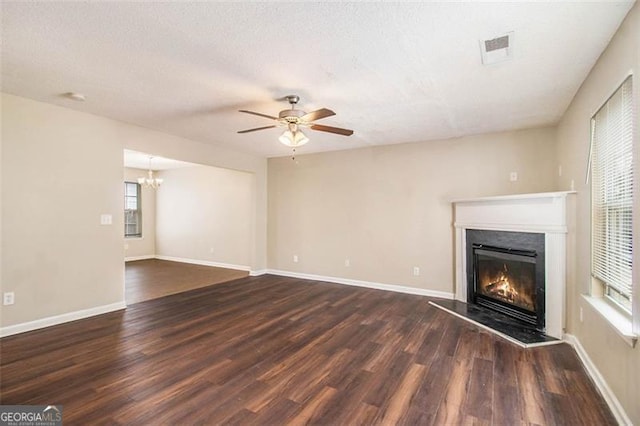 unfurnished living room with dark hardwood / wood-style floors, ceiling fan with notable chandelier, and a textured ceiling