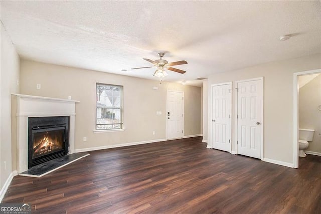 unfurnished living room with ceiling fan, dark hardwood / wood-style floors, and a textured ceiling