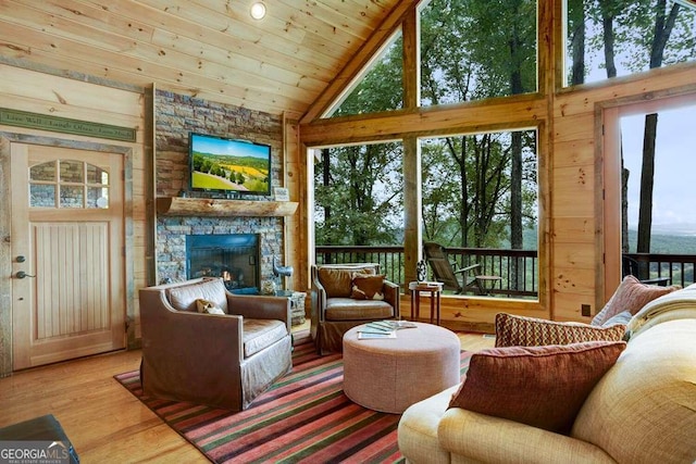 living room with wood ceiling, high vaulted ceiling, a stone fireplace, and hardwood / wood-style floors