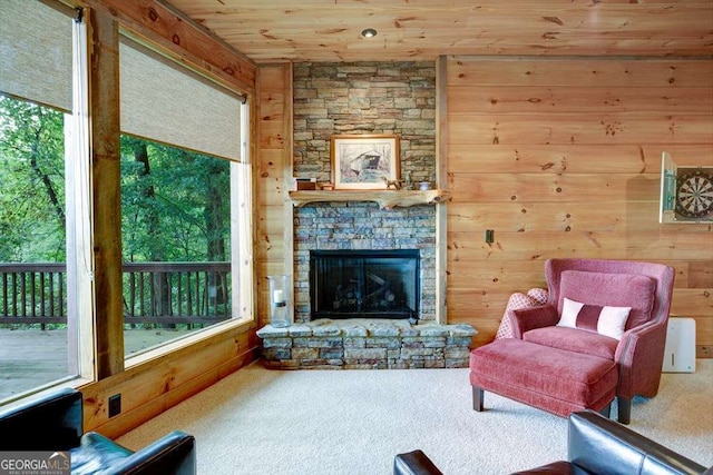 living room with carpet floors, a fireplace, wooden walls, and wooden ceiling