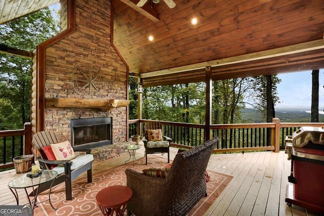 deck featuring ceiling fan and an outdoor stone fireplace