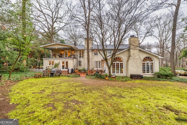 rear view of property with a balcony and a yard