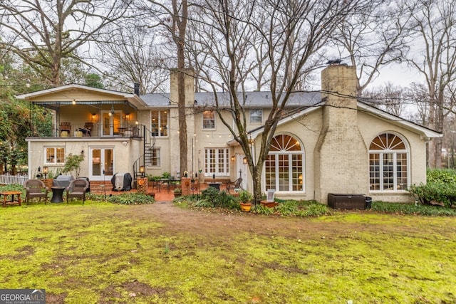 back of house with a balcony and a yard