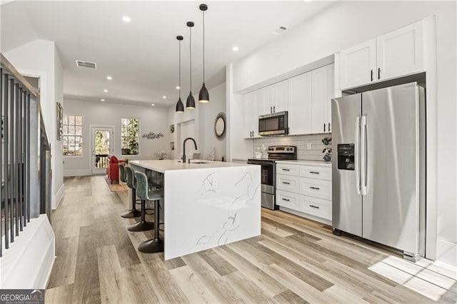 kitchen with a sink, decorative backsplash, appliances with stainless steel finishes, and white cabinetry