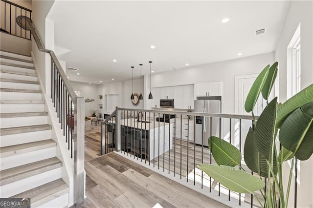 stairway featuring visible vents, recessed lighting, and wood finished floors