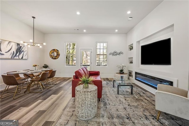 living room featuring a chandelier, recessed lighting, baseboards, and wood finished floors