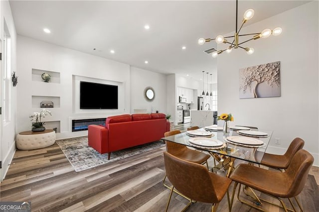 dining room with recessed lighting, baseboards, an inviting chandelier, and wood finished floors
