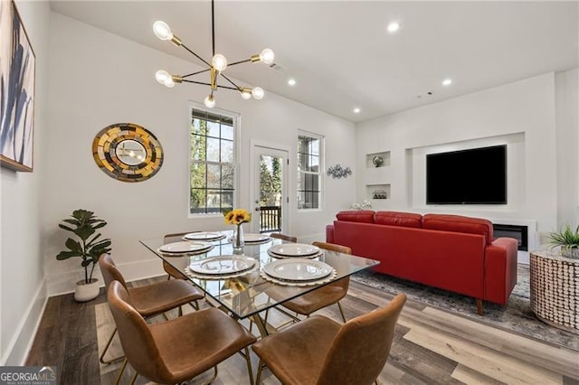 dining space featuring a chandelier, recessed lighting, baseboards, and wood finished floors