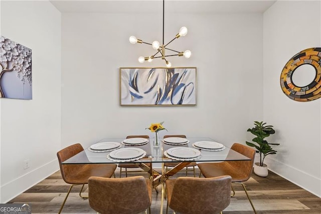 dining area with baseboards, an inviting chandelier, and wood finished floors