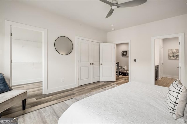 bedroom featuring wood finished floors, baseboards, two closets, and connected bathroom