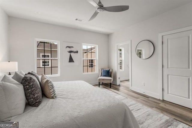 bedroom with visible vents, wood finished floors, baseboards, and ceiling fan
