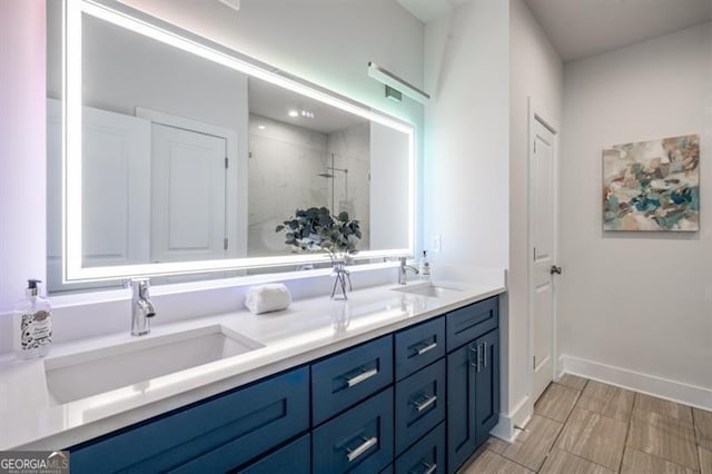 full bath featuring double vanity, a stall shower, baseboards, and a sink