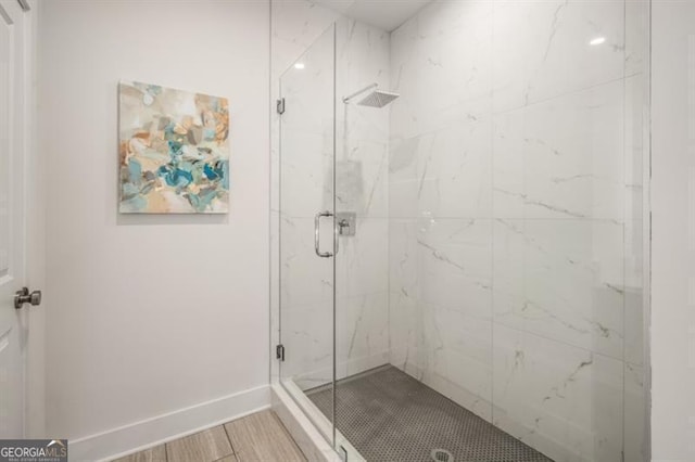 bathroom with a marble finish shower and baseboards
