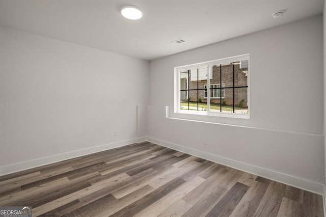 unfurnished room featuring wood finished floors, baseboards, and visible vents