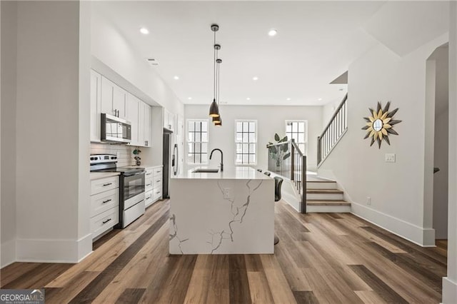 kitchen with a sink, tasteful backsplash, light wood-style floors, appliances with stainless steel finishes, and white cabinets