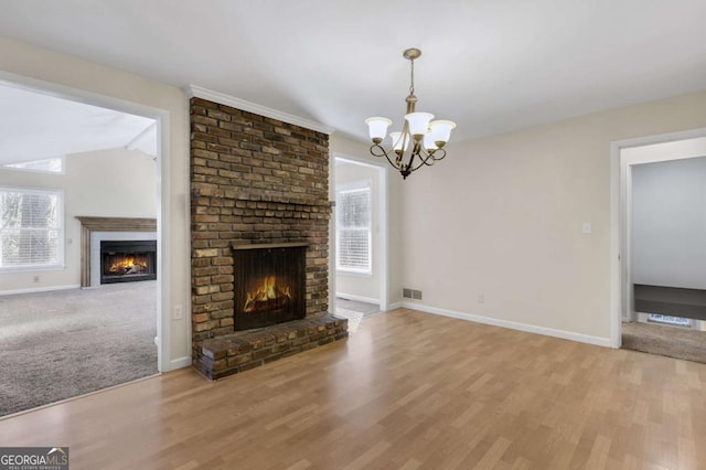 unfurnished living room featuring a brick fireplace, baseboards, visible vents, and a wealth of natural light