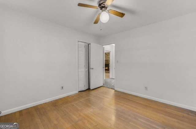 unfurnished bedroom featuring hardwood / wood-style floors, a closet, a ceiling fan, and baseboards