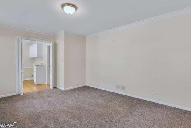 unfurnished room featuring light colored carpet, crown molding, visible vents, and baseboards