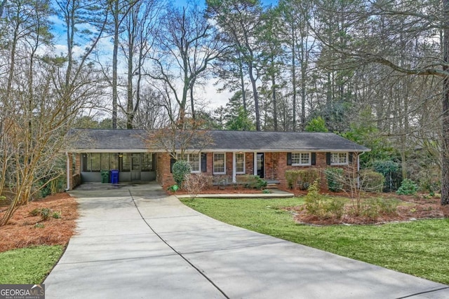 single story home with a front yard, concrete driveway, brick siding, and an attached carport