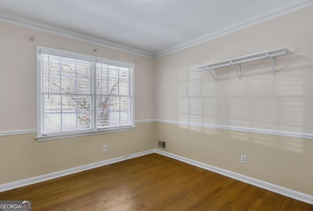 unfurnished room featuring ornamental molding, visible vents, baseboards, and wood finished floors