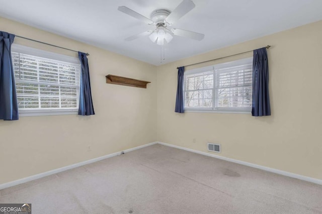 unfurnished room with carpet floors, plenty of natural light, visible vents, and baseboards