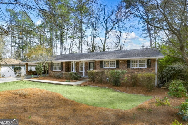 single story home featuring driveway, brick siding, and a front yard