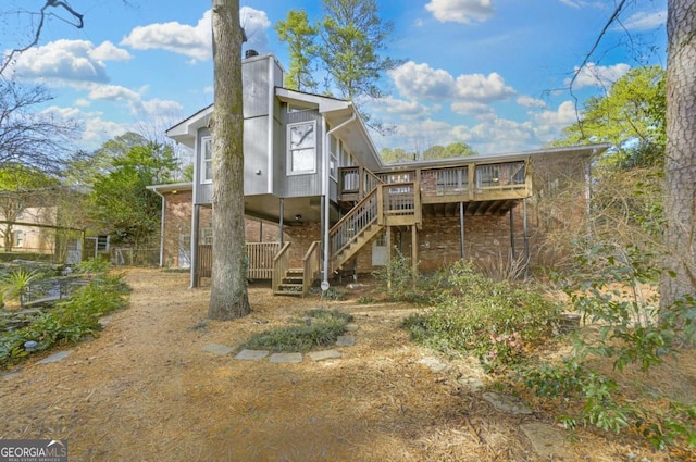 back of property with stairs, a chimney, and a wooden deck