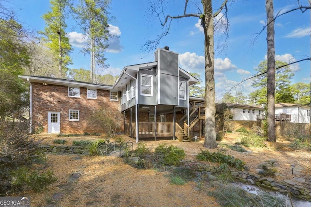 rear view of house featuring brick siding and a chimney