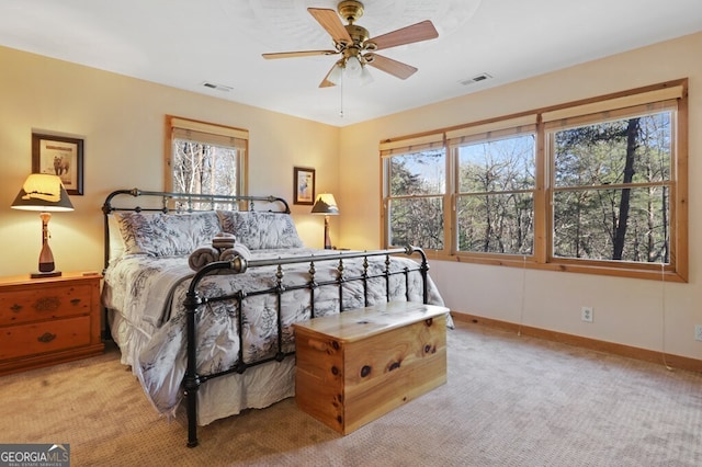 carpeted bedroom featuring a ceiling fan, visible vents, and baseboards