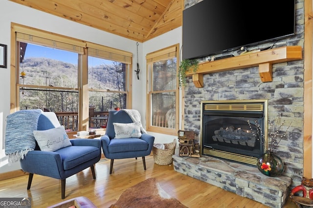 living area with lofted ceiling, wood ceiling, a fireplace, and wood finished floors