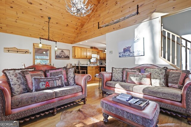 living room featuring a notable chandelier, high vaulted ceiling, stairway, and light wood-style floors