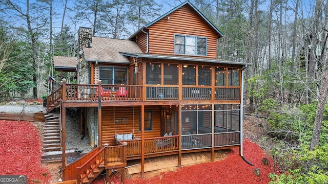 back of house with a sunroom, a chimney, stairway, and log veneer siding