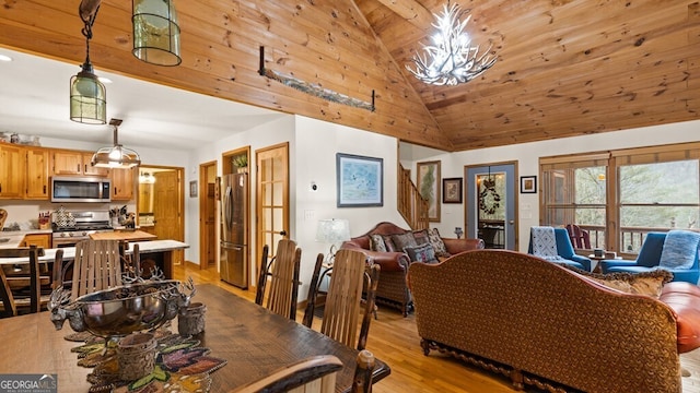 dining space featuring light wood-style floors, high vaulted ceiling, and an inviting chandelier