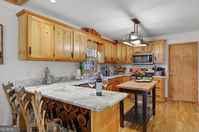 kitchen featuring stainless steel appliances, recessed lighting, light wood-style flooring, a peninsula, and a kitchen breakfast bar