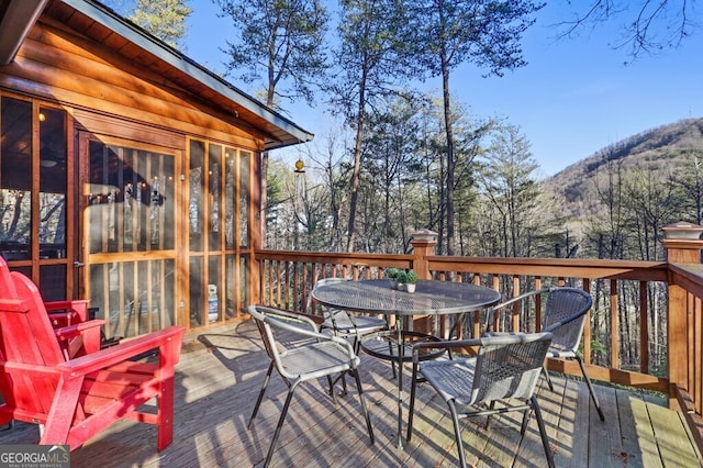 wooden deck with a mountain view and outdoor dining space