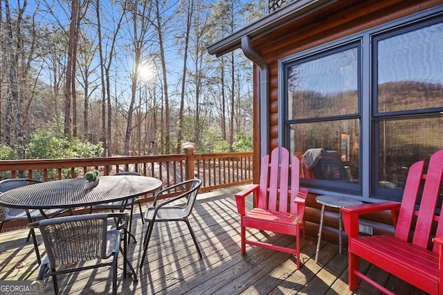 wooden deck with a forest view and outdoor dining area