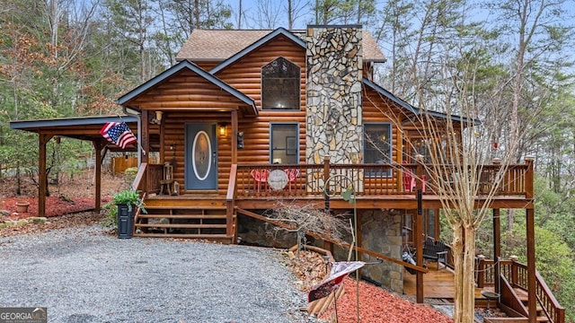 view of front facade featuring stone siding, a shingled roof, and a deck